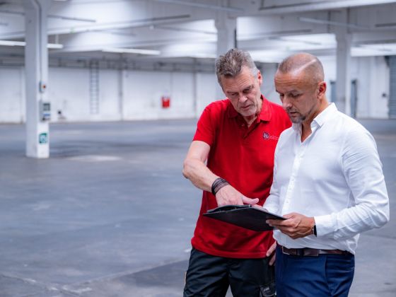 Bauleitung vor Ort: Elektriker und Projektleiter von Eulektra prüfen Planungsunterlagen in einer Halle